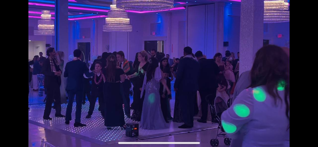 Guests dancing under colorful wedding lights